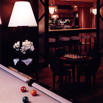 Dimly lit room with pool table and chess set at the Rose Bar