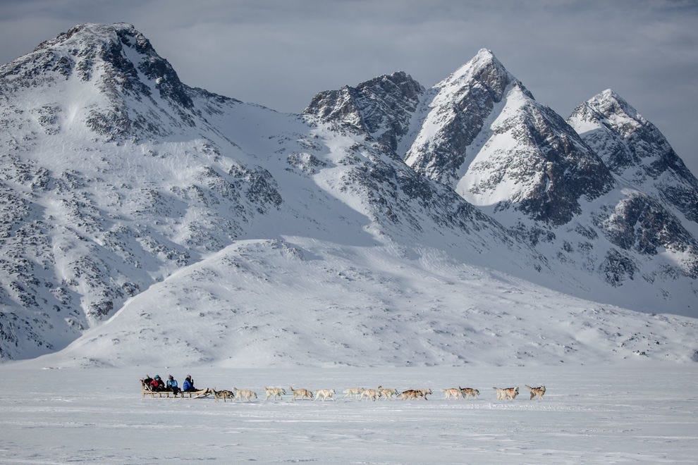 Traîneau à chiens sous des pics éloignés dans la partie Tasiilaq de l'Est du Groenland